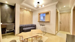 A modern living room with a sofa, a dining table, and a TV mounted on the wall. - Bomma Residencies  (Abuja)