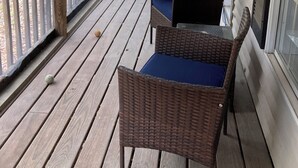 A wooden deck with wicker furniture and a view of a forest.