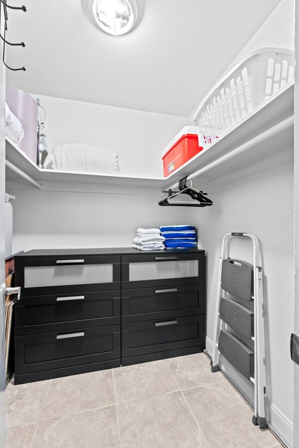 Un espacio de almacenamiento compacto con un aparador negro, una caja roja de almacenamiento y una escalera blanca.
