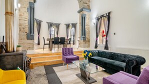 A spacious living area with a stone fireplace, a glass coffee table, and a plush green sofa. - 5 bedroom accommodation in Rossendale (Rossendale)