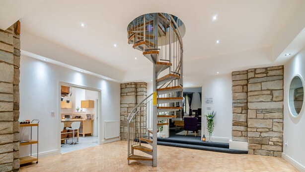A spacious interior with a spiral staircase, stone walls, and a herringbone wooden floor. - 5 bedroom accommodation in Rossendale (Rossendale)