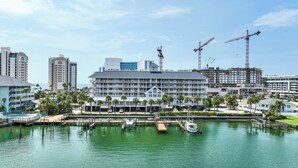 A waterfront hotel with multiple balconies, a marina, and construction cranes in the background. - Ocean Front Beach in Clearwater 2BB 2BA  (Clearwater Beach)
