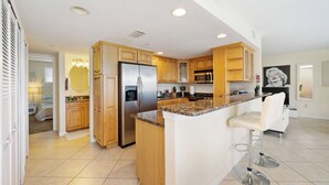 A modern kitchen with wooden cabinets, stainless steel appliances, and a granite countertop. - Ocean Front Beach in Clearwater 2BB 2BA  (Clearwater Beach)