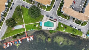 Vue aérienne d’un quartier résidentiel avec une piscine, un court de tennis et un quai où sont amarrés des bateaux.