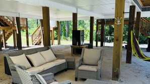 Een overdekt terras met rieten meubels, een televisie en een hangmat.