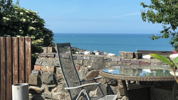 Une terrasse avec une chaise et une table en métal, donnant sur la mer.