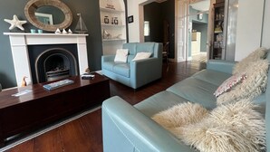 Un salon avec une cheminée, un canapé bleu clair, une table basse en bois foncé et un lustre.