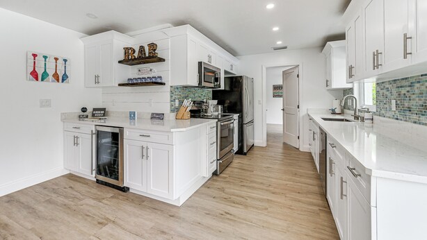 A modern kitchen with white cabinetry, stainless steel appliances, and a wooden floor. - Naples Escape w/ Furnished Patio & Private Pool! (Naples)