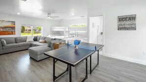 A modern living room with a ping pong table, gray sofas, and a view of the outdoors. - Naples Escape w/ Furnished Patio & Private Pool! (Naples)