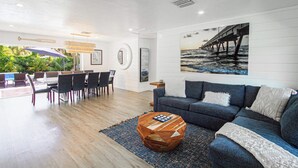 A modern living room with a dining area, a blue sofa, and a wooden coffee table. - Naples Escape w/ Furnished Patio & Private Pool! (Naples)