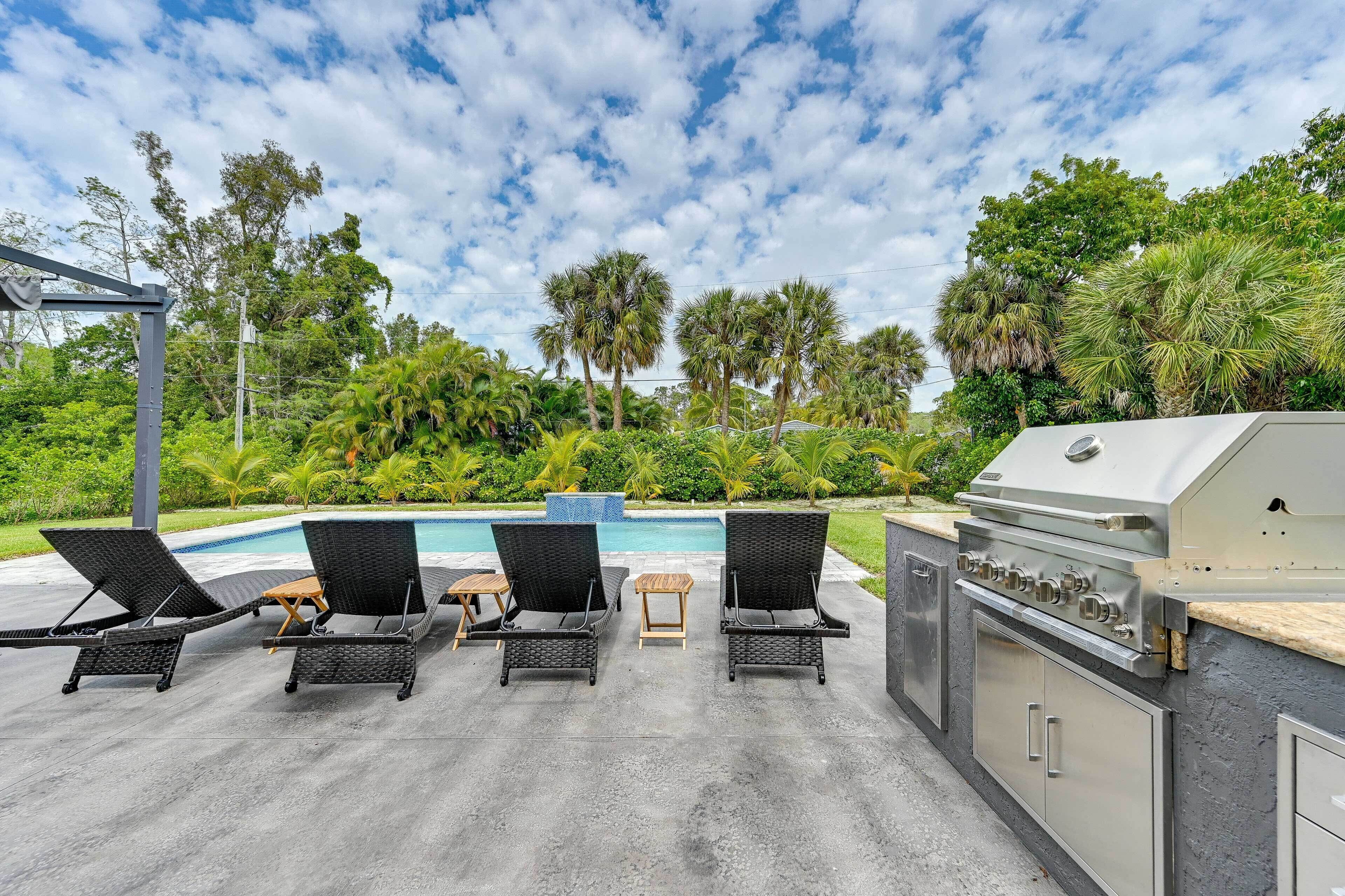 An outdoor patio with lounge chairs, a barbecue grill, and a swimming pool.