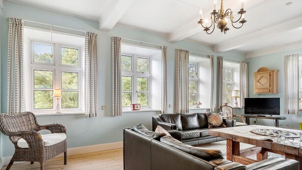 A well-lit living room with a sofa, a wicker chair, a dining table, and a TV. - Gorgeous home in Bredebro with WiFi (Bredebro)