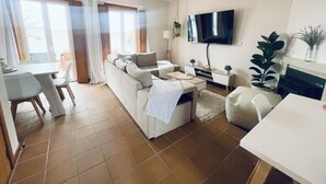 A modern living room with a sofa, TV, and dining area. - Casa Sonia Great location Quiet area Easy access (Óbidos)