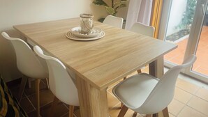 A dining area with a wooden table, white chairs, and a glass jar with a rope decoration on it. - Casa Sonia Great location Quiet area Easy access (Óbidos)