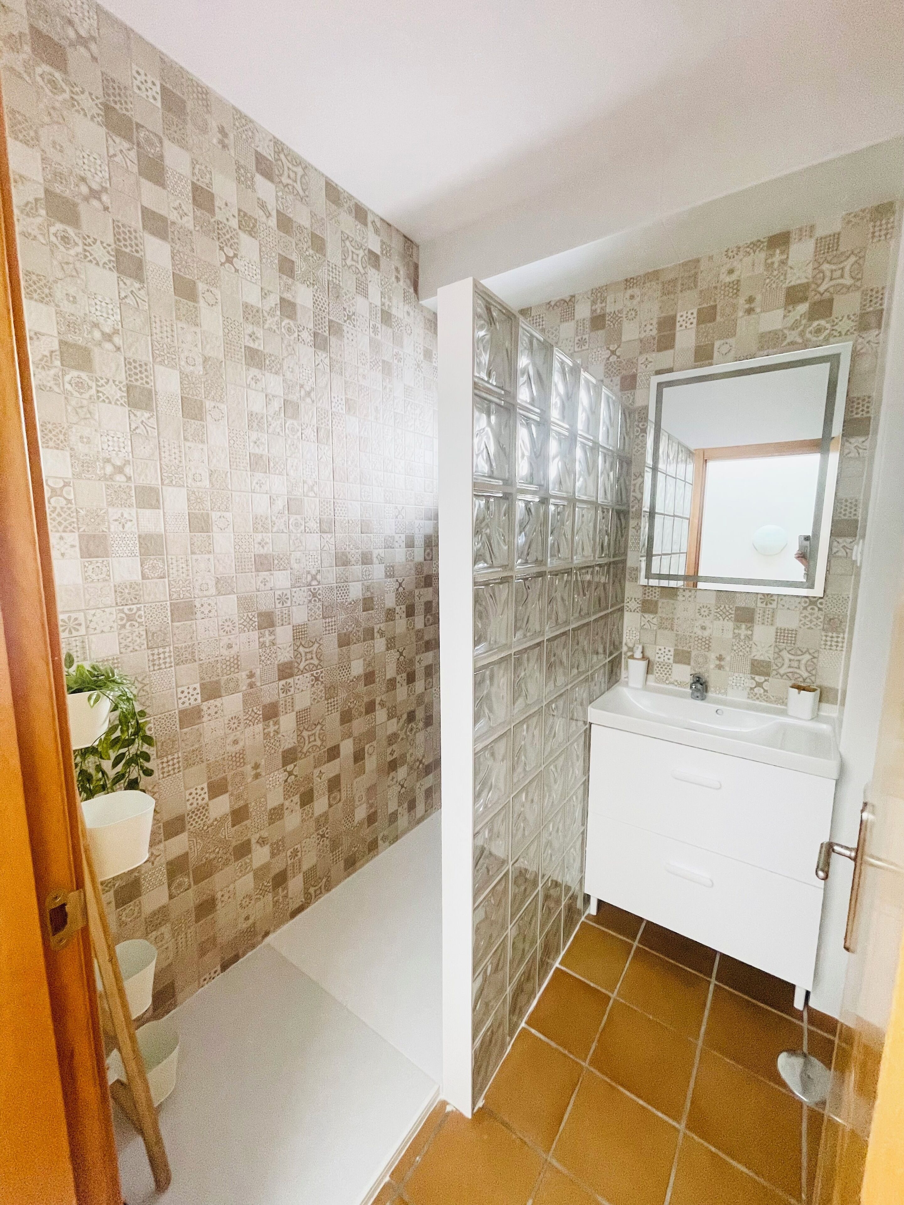 A bathroom with patterned tiles, a white sink, and a mirror.