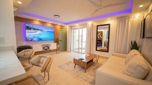 A modern living room with a flat-screen TV, a ceiling fan, and a sofa. - Garden Condos 5- Luxurious Apartment In Sosua Center! (Sosúa)
