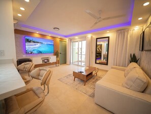 A modern living room with a flat-screen TV, a ceiling fan, and a sofa. - Garden Condos 5- Luxurious Apartment In Sosua Center! (Sosúa)