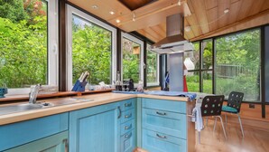 A modern kitchen with large windows, wooden cabinets, and a central island.