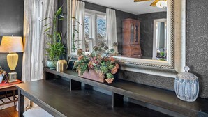 Une pièce dotée d’un parquet en bois foncé, d’un grand miroir, d’un ventilateur de plafond et d’une fenêtre avec des rideaux.