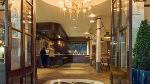 Ein Restaurant mit Barbereich, einer Kristallleuchtre und einer Theke, hinter der eine Person steht.
