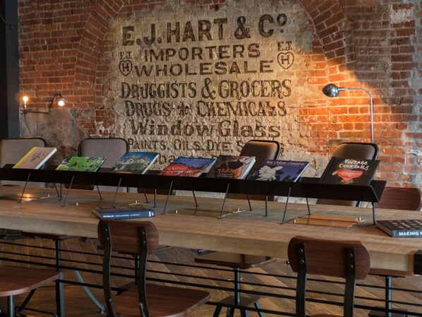 Eine Ziegelwand mit einem Schild im Vintage-Stil, das die Dienstleistungen von E.J. Hart & Co. auflistet.
