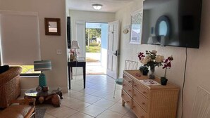 A living room with a sofa, a coffee table, a wicker dresser, a chair, and a TV mounted on the wall. - Port St Lucie 3BD -2B (Port Saint Lucie)