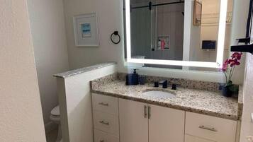 A bathroom with a large mirror, a sink, and a toilet.
