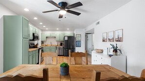 Una cucina moderna con mobili verdi, un tavolo da pranzo in legno e una ventola a soffitto.