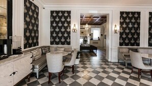 Un sol à carreaux, un canapé, une table à manger et un lustre dans le hall d’un hôtel.