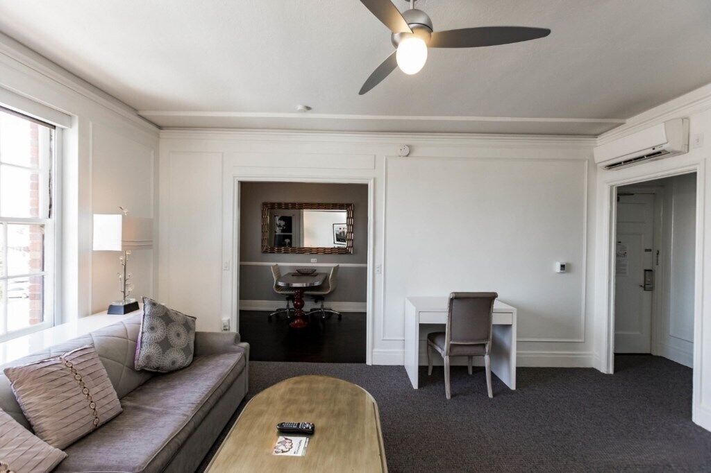 A modern living room with a sofa, coffee table, and a desk area.