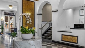 Un hall d’entrée avec un comptoir de réception en marbre, un escalier et un sol à carreaux.