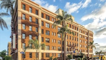 A multi-story hotel with a brick facade, multiple windows, and a parking lot with several cars.