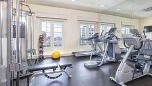 Uma academia com equipamentos de ginástica, um banco e uma bola de exercícios amarela.