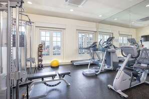 Ein Fitnessraum mit Trainingsgeräten, einer Bank und einem gelben Trainingsball.