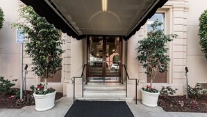 A hotel entrance with a covered entrance, steps leading to a glass door, and potted plants on either side. - San Diego | San Diego Zoo Trip | Hot Tub & Rooftop Deck (San Diego)