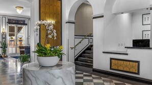 A lobby with a marble column, a staircase, and a reception desk. - San Diego | San Diego Zoo Trip | Hot Tub & Rooftop Deck (San Diego)
