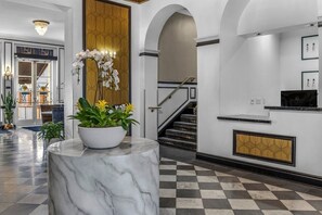 A lobby with a marble column, a staircase, and a reception desk.