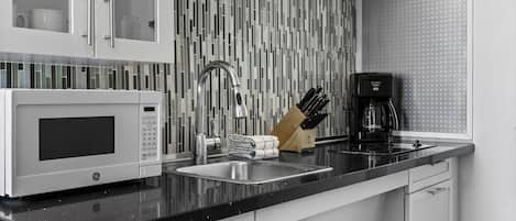 A modern kitchen with a built-in microwave, stainless steel sink, and a coffee maker.