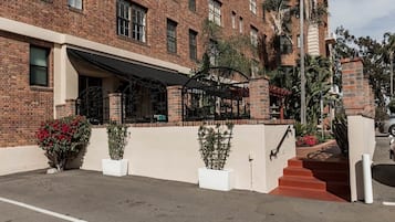 A brick building with a covered outdoor seating area, a staircase, and potted plants.