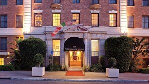 A brick building with a sign for 'Park Manor Suites' at the entrance, featuring a grand archway and a red carpet. - San Diego | Parkside Weekend | Hot Tub & Rooftop Deck (San Diego)