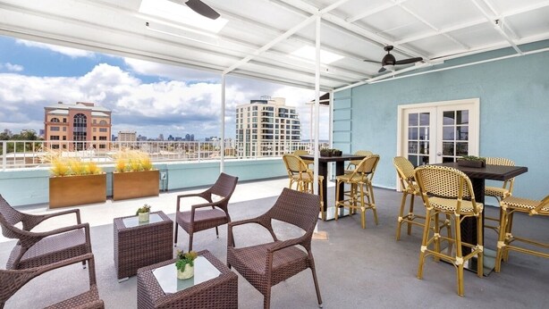A rooftop terrace with wicker furniture, a dining table, and potted plants. - San Diego | San Diego Park Trip | Hot Tub & Rooftop Deck (San Diego)