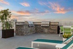 An outdoor patio with a stone barbecue and lounge chairs. - San Diego | San Diego Park Trip | Hot Tub & Rooftop Deck (San Diego)