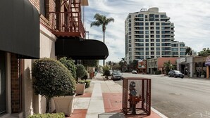 A street view with a building featuring a black awning, potted plants, and a fire hydrant. - San Diego | San Diego Park Trip | Hot Tub & Rooftop Deck (San Diego)