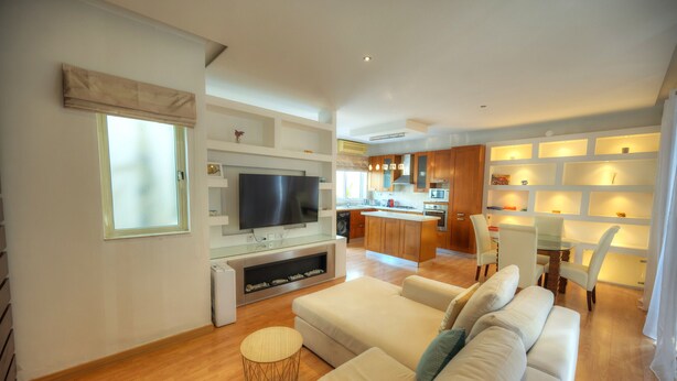 Una sala de estar moderna con un sofá, televisor y un comedor con sillas y una mesa.