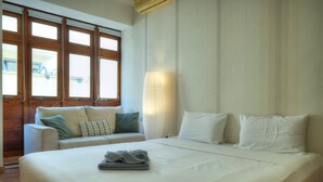 Una habitación de hotel con una cama grande, un sofá y una ventana con marcos de madera.