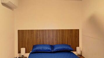 Un dormitorio con una cama, un cabecero de madera, dos mesitas de noche con lámparas y un ventilador de techo.