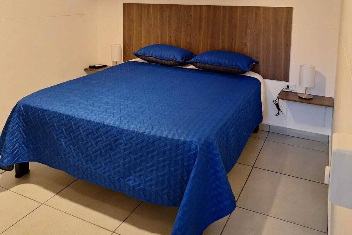 A bedroom with a bed, a ceiling fan, a nightstand, and a wall-mounted air conditioner.