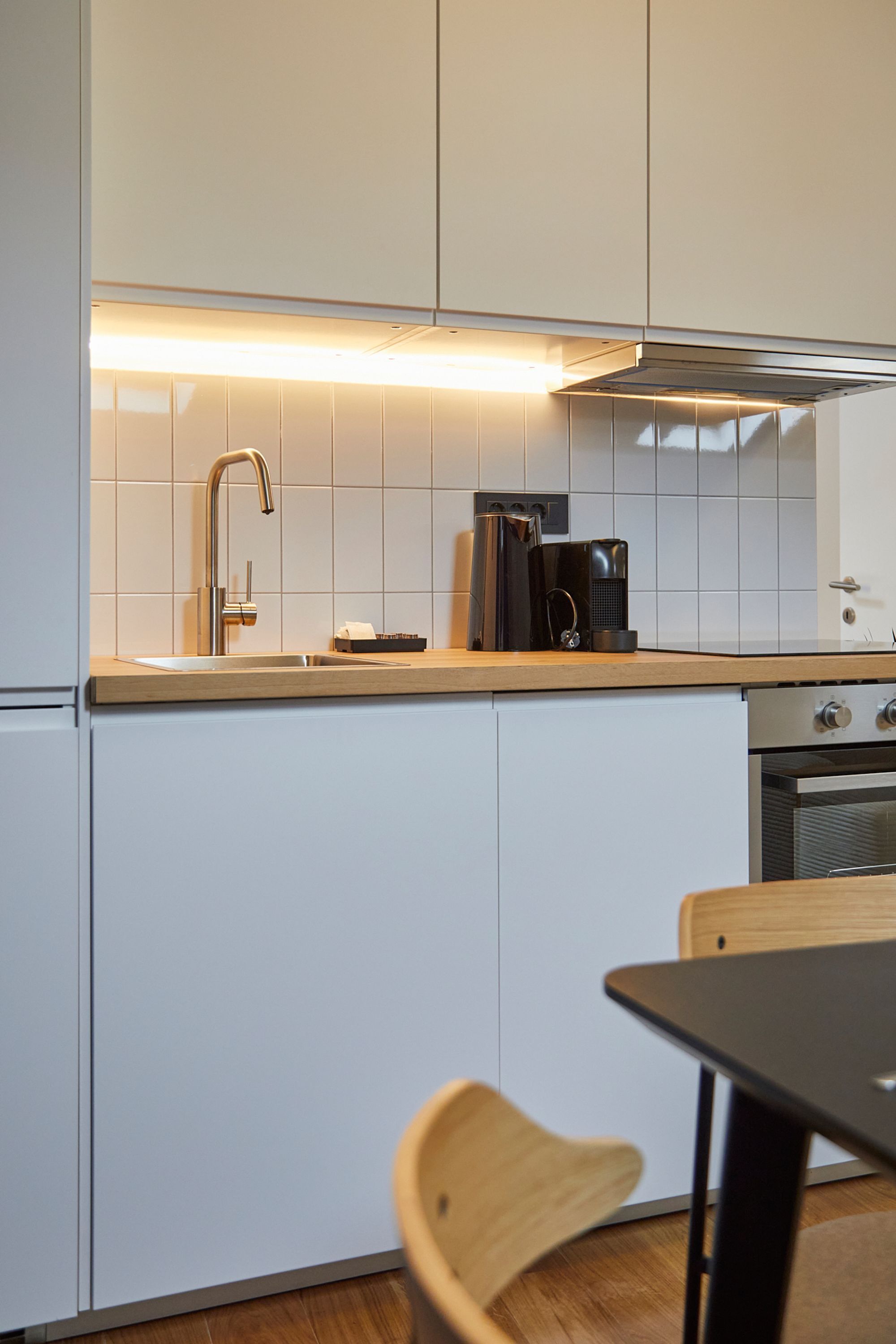 A modern kitchen with white cabinets, a stainless steel sink, and a coffee maker.