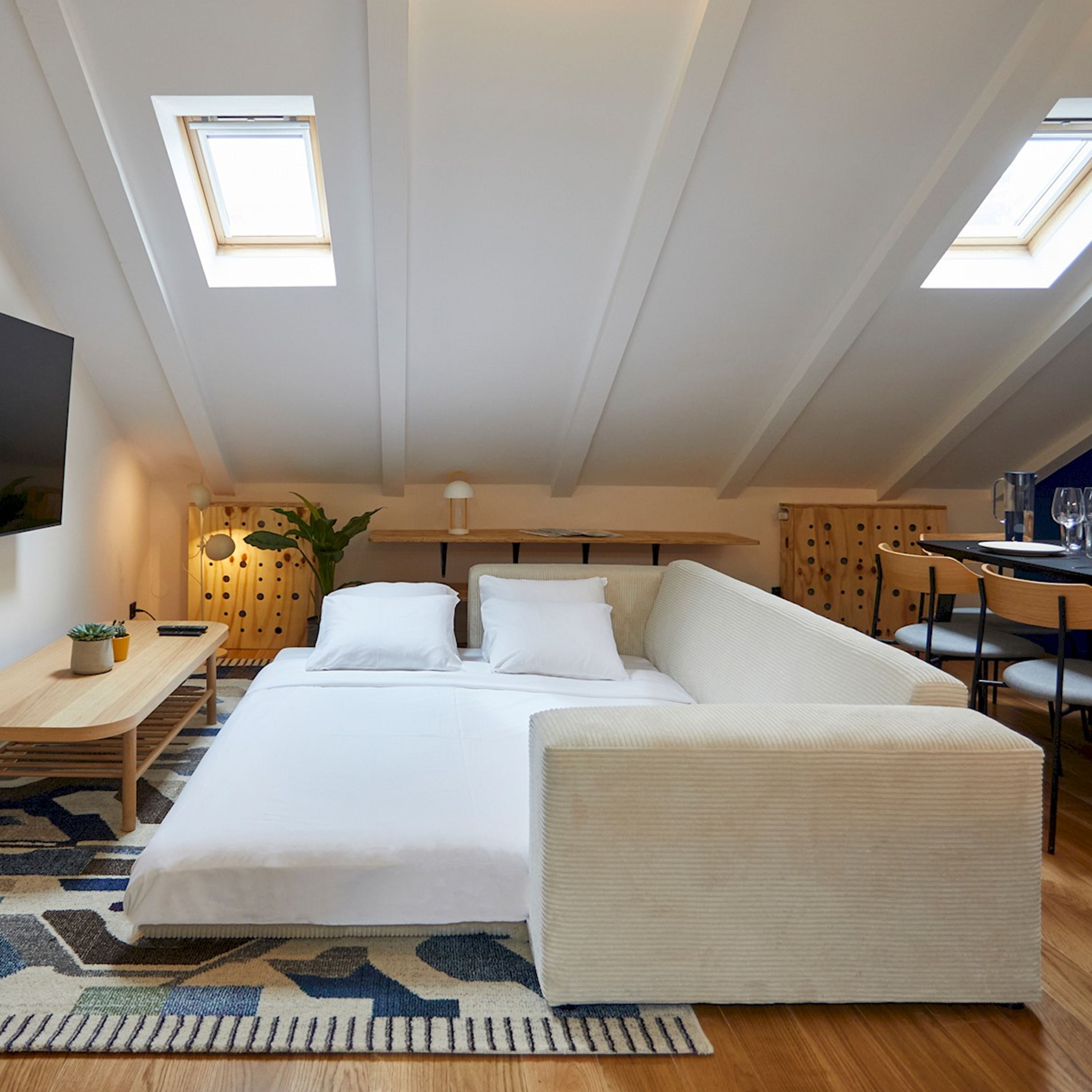 Ein modernes Schlafzimmer mit Bett, Schreibtisch und Essecke.
