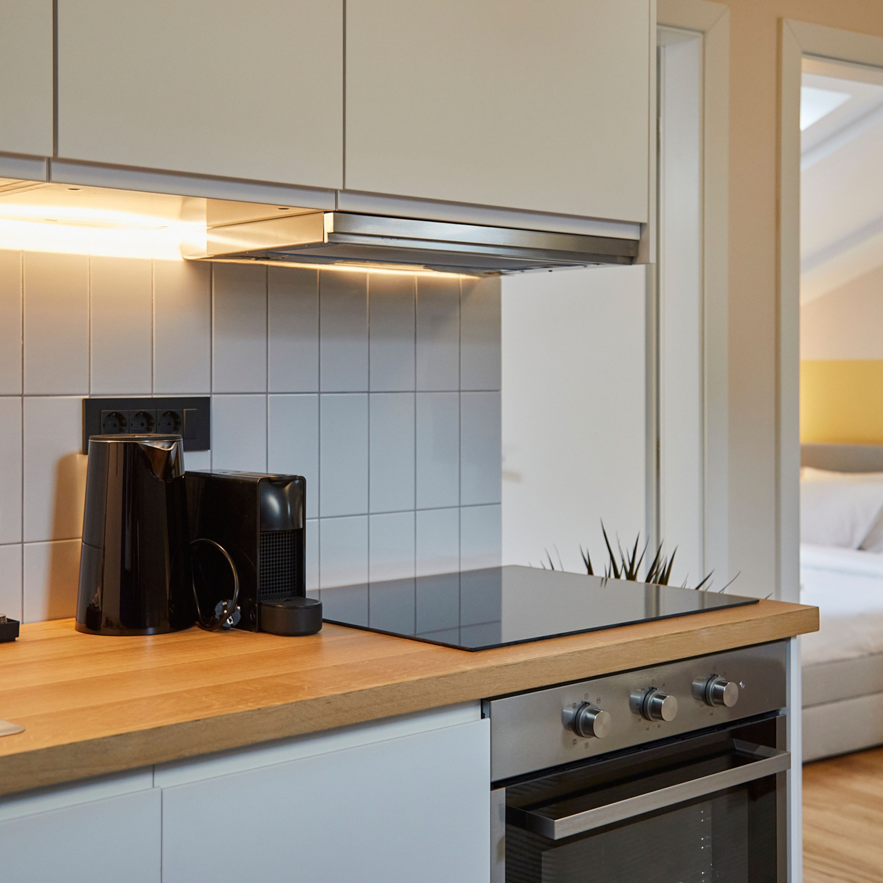 Een moderne keuken met een ingebouwde kookplaat, oven en koffiezetapparaat.